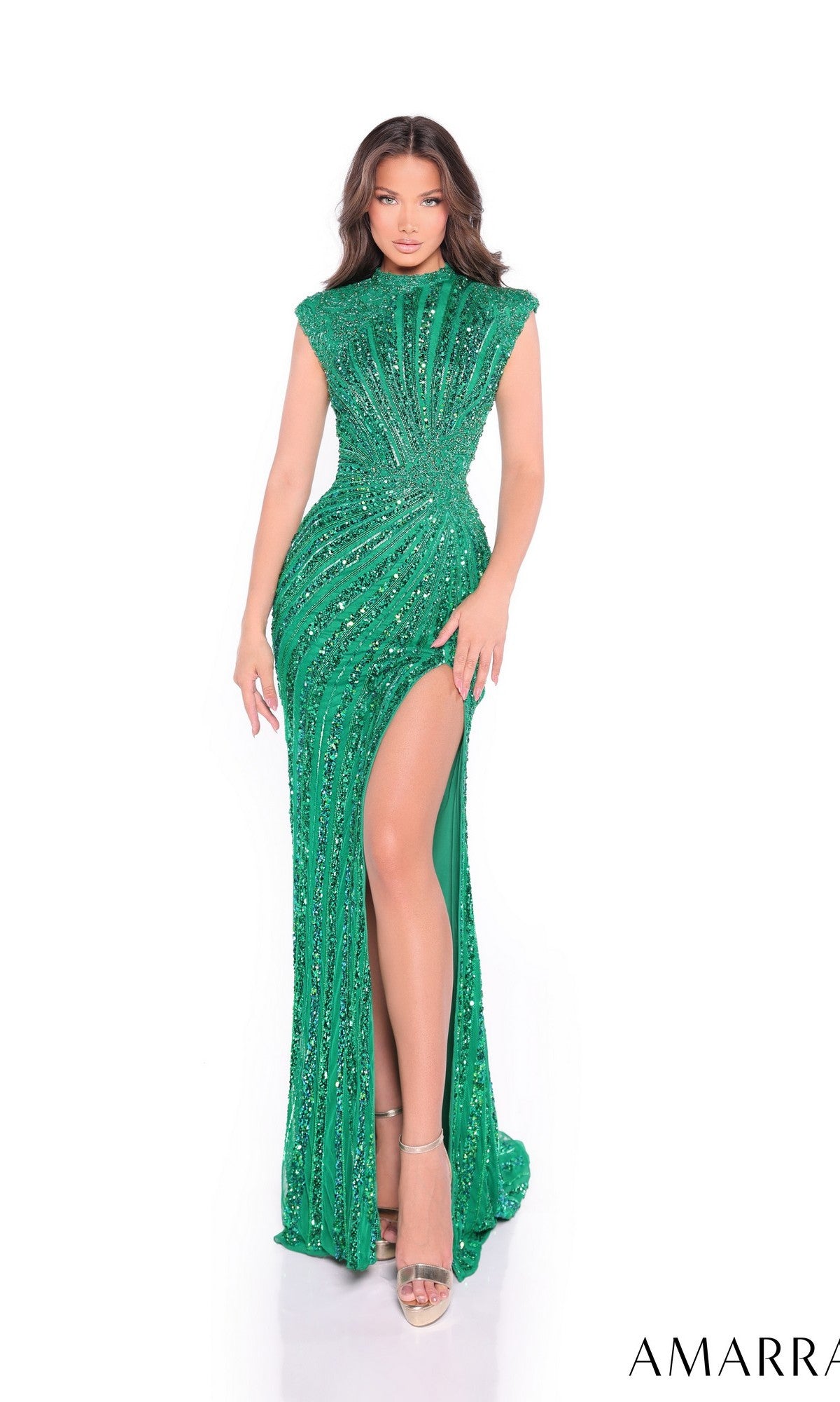 A woman in the Amarra 89177 long prom dress, featuring a fitted emerald green design with sequin embellishments, a high slit, and an elegant open back, stands against a white background.